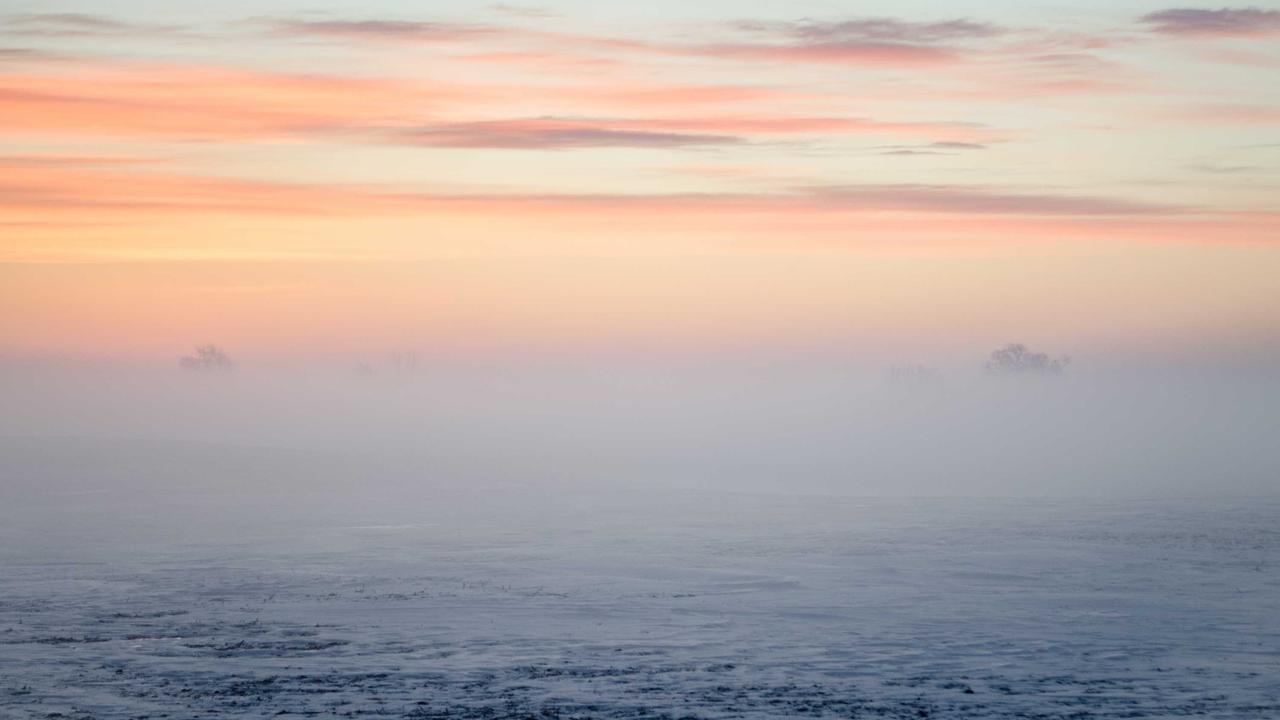 A space tourist looking out of a large circular window at the Earth