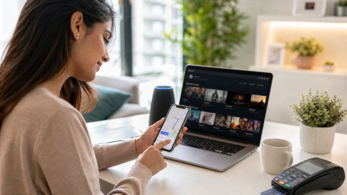 Person using smartphone and laptop with AI-powered navigation, streaming, and digital payments